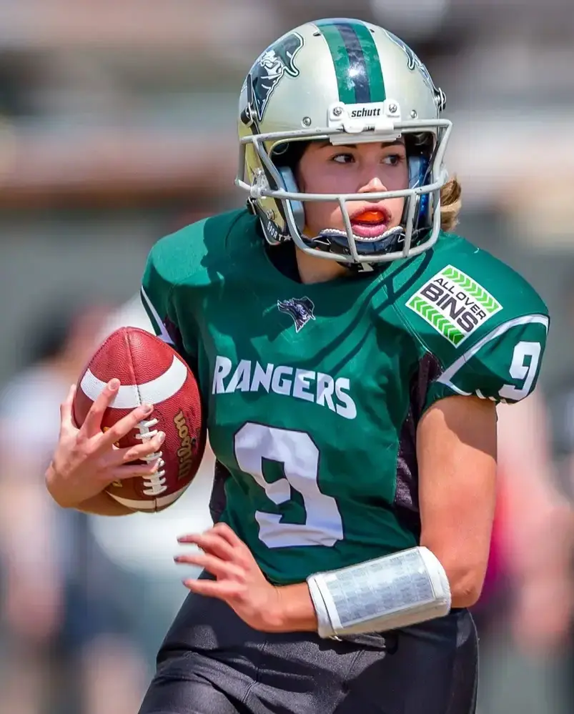 female wearing custom green American football uniform playing in football field