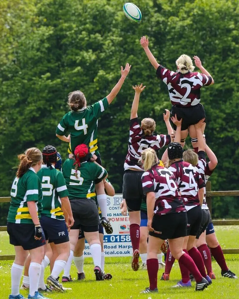 girls school team wearing custom rugby green and maroon uniform playing in ground